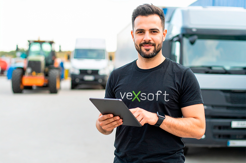 Profissional com tablet em frente a caminhões, trator e van, representando diferentes segmentos atendidos pelo VEXSOFT